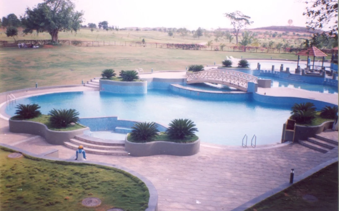 A landscaped recreational water body and pool with a bridge feature