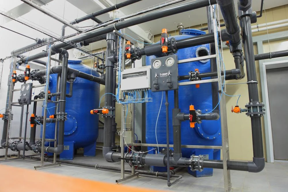 Industrial water treatment plant interior with pressure vessels and pipework